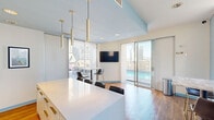 Located in the heart of downtown Dallas at 1509 Main Street, this rooftop space combines a contemporary kitchen with expansive outdoor amenities and stunning city skyline views. The interior kitchen area features a large white quartz island with gold-accented cabinetry, warm hardwood flooring, and soft blue accent walls that lend a clean, modern aesthetic. Pendant lighting with brass cylindrical fixtures hangs overhead, complementing the upscale finishes throughout. Floor-to-ceiling sliding glass doors connect the interior seamlessly to the outdoor terrace, flooding the space with natural light and framing panoramic views of the Dallas skyline.

The rooftop exterior offers multiple distinct zones for entertaining. A spacious pool deck features a bright, resort-style swimming pool surrounded by a grey composite deck and lounge areas. An al fresco dining and grilling area is positioned alongside the building's ornate historic stone facade, complete with outdoor bar seating and a full grill station. The juxtaposition of the building's classic Gothic-inspired architectural detailing against the modern Dallas skyline creates a striking visual backdrop throughout the outdoor space. A wall-mounted TV in the dining area adds a functional element for gatherings. This rooftop venue is ideal for events, social functions, or relaxed urban entertaining.