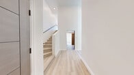 Located at 154 S Occidental Blvd in Los Angeles, this modern two-story unit offers a thoughtfully designed layout spread across two levels. The main floor features an open-concept living and kitchen area bathed in natural light from dramatic floor-to-ceiling windows that frame sweeping panoramic views of the Los Angeles skyline and surrounding neighborhood. The contemporary kitchen is equipped with stainless steel appliances, including a full-size refrigerator, microwave, and range, complemented by warm, flat-front cabinetry and a sleek sink. Light hardwood flooring runs throughout both levels, enhancing the unit's bright and airy aesthetic. A staircase with a modern metal railing connects the main level to the upper loft-style floor, which provides additional flexible living space. The private bedroom is a tranquil retreat with clean white walls, a corner window inviting natural light, and polished hardwood floors. Distinctive wood-paneled interior doors add a warm, contemporary touch throughout. The full bathroom features mosaic tile flooring, a modern floating vanity with a white countertop, and a separate walk-in shower. Recessed lighting and a clean, neutral palette complete the refined, modern feel of this well-appointed Los Angeles residence.