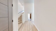 Located at 154 S Occidental Blvd in Los Angeles, this modern two-story unit offers a thoughtfully designed layout spread across two levels. The main floor features an open-concept living and kitchen area bathed in natural light from dramatic floor-to-ceiling windows that frame sweeping panoramic views of the Los Angeles skyline and surrounding neighborhood. The contemporary kitchen is equipped with stainless steel appliances, including a full-size refrigerator, microwave, and range, complemented by warm, flat-front cabinetry and a sleek sink. Light hardwood flooring runs throughout both levels, enhancing the unit's bright and airy aesthetic. A staircase with a modern metal railing connects the main level to the upper loft-style floor, which provides additional flexible living space. The private bedroom is a tranquil retreat with clean white walls, a corner window inviting natural light, and polished hardwood floors. Distinctive wood-paneled interior doors add a warm, contemporary touch throughout. The full bathroom features mosaic tile flooring, a modern floating vanity with a white countertop, and a separate walk-in shower. Recessed lighting and a clean, neutral palette complete the refined, modern feel of this well-appointed Los Angeles residence.
