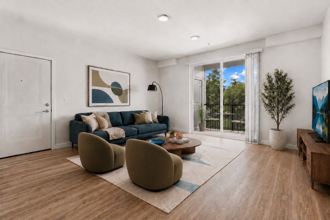 Staged living room illustrating a comfortable furniture layout with direct access to the private balcony. - 27 West Apartments