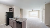 Located at 3340 Shipley St in North Charleston, SC, this well-appointed 2-bedroom, 2-bathroom single-floor residence offers a thoughtfully designed layout across a comfortable footprint. The kitchen is a standout feature, showcasing dark espresso cabinetry, granite countertops, wood-look tile flooring, and black appliances including a range, microwave, refrigerator, and dishwasher. A peninsula with an integrated sink and additional seating space connects the kitchen seamlessly to the open-concept living area. The living room is generously sized, featuring plush neutral carpet, a ceiling fan, and a large window that invites abundant natural light. Both bedrooms are carpeted and well-lit, each offering windows with neighborhood views and convenient closet storage. The primary bedroom is notably spacious with direct access to its en-suite bathroom. Both bathrooms are finished with granite-topped dark wood vanities, tub-shower combinations, and light wood-look flooring, providing a clean and cohesive aesthetic. A connecting hallway ties all areas of the home together efficiently. The overall design emphasizes neutral tones, consistent finishes, and functional flow throughout.