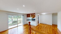 Located at 7940 Janes Ave in Woodridge, IL, this one-bedroom, one-bathroom unit offers a thoughtfully designed layout with warm hardwood floors throughout. The open-plan living and kitchen area forms the heart of the space, bathed in natural light from large sliding glass doors that lead out to a private deck overlooking a lush green outdoor setting. Recessed lighting illuminates the living area, which also features a wall-mounted mini-split system and baseboard heating for year-round comfort. The kitchen is well-appointed with rich wood cabinetry — including glass-front upper cabinets — granite countertops, a double-basin sink, and stainless steel appliances including a dishwasher and range. A classic wood staircase with a turned-post banister adds a timeless architectural detail to the main level. The spacious bedroom features polished hardwood floors, a ceiling fan, a window with garden views, and a wall-mounted mini-split unit. The bathroom area includes in-unit stacked washer and dryer alongside marble-look tile flooring, adding convenience to daily living. A dedicated closet completes the unit's practical layout, making this a well-rounded and functional home in a serene suburban setting.
