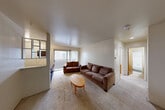 Located at 323 Packard St in Ann Arbor, MI, this one-bedroom, two-bathroom unit offers a practical and well-organized single-floor layout. The combined living and dining area serves as the heart of the home, featuring carpet flooring, neutral white walls, and a sliding glass door that opens onto a private balcony, allowing natural light to fill the space. A distinctive open pass-through with a grid-style partition connects the living area to the kitchen, providing visual openness while maintaining a clear functional division. The kitchen includes standard appliances and dark flooring, contrasting the carpeted living areas. A welcoming hallway guides residents from the light blue entry door toward the rest of the unit. The generously sized bedroom is notably bright, benefiting from two windows with vertical blinds and baseboard heating. A full wall of built-in cabinetry provides extensive storage throughout the bedroom. Two additional closets offer further organizational options. Both bathrooms are functional, with one featuring classic white subway tile surrounding a full bathtub and shower. Baseboard heating is present throughout the unit, and the overall layout is efficiently designed to maximize the use of available space.