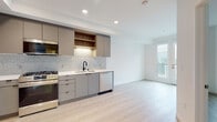 Located at 310 Del Sol Dr in San Diego, CA, this single-floor residence showcases a clean, contemporary design with a cohesive aesthetic throughout. The open-concept layout connects the kitchen and living area, creating a spacious and functional flow. Light-toned hardwood-style flooring runs throughout the unit, enhancing the bright, airy atmosphere complemented by recessed lighting overhead.

The kitchen is a standout feature, outfitted with flat-front gray cabinetry, warm wood open shelving, and a textured mosaic tile backsplash. Stainless steel appliances include a gas range, built-in microwave, dishwasher, and full-size refrigerator, all set against light quartz countertops. A matte black faucet adds a modern accent at the sink. The living area extends naturally from the kitchen, with access to a private balcony through a glass door, bringing in natural light.

The bathroom features large-format white tile surrounding a soaking tub and shower combination, with a built-in recessed niche for storage, maintaining the minimalist aesthetic. The remaining rooms offer clean white walls and generous proportions, ideal as bedrooms or flexible living spaces. The overall design is modern, light-filled, and move-in ready, reflecting the contemporary residential character of the San Diego area.