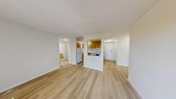 This 2-bedroom, 2-bathroom unit in Calgary, AB offers a practical and comfortable single-floor layout. Light hardwood flooring runs throughout, creating a bright and cohesive feel across all rooms. The open-concept living and dining area is generously sized, with natural light streaming in through a large window that overlooks the private balcony — a pleasant outdoor extension of the living space. The kitchen is semi-enclosed, featuring warm honey-toned wood cabinetry, white appliances including a refrigerator and electric range, a tile backsplash, and ample counter and storage space. The entrance leads into a hallway that connects the main living areas to the bedrooms and bathrooms. The primary bedroom is a comfortable size and benefits from a large sliding window with views of surrounding greenery. The second bedroom is equally bright, with natural light and room for various configurations. Both bathrooms are finished with beige ceramic tile surrounding deep soaker tubs with shower fixtures, complemented by light wood-style flooring. A dedicated closet provides additional storage. Textured ceilings and baseboard heating are consistent throughout the unit, adding to its functional character.