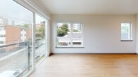 Located at 110 Roy St in Seattle's Lower Queen Anne neighborhood, this efficiently designed studio offers a thoughtfully organized single-floor layout. The combined kitchen and living area serves as the heart of the space, bathed in natural light from large sliding glass doors that open to a private balcony overlooking the surrounding neighborhood's greenery and streetscape. A picture window further enhances the bright, airy atmosphere of the living area, which is finished with light hardwood-style flooring throughout.

The kitchen is well-appointed with warm wood-toned cabinetry, white subway tile backsplash, white quartz countertops, and a full suite of stainless steel appliances including an electric range, microwave, and dishwasher. A peninsula counter provides added workspace and a natural division between the kitchen and living areas. A wall-mounted mini-split unit ensures year-round climate comfort.

The hallway connects the living space to the bathroom and closet. The bathroom features a full soaking tub and shower combination with clean white tile surround, contemporary chrome fixtures, and matching hardwood-style flooring. Recessed lighting throughout adds a polished, modern touch. The dedicated closet provides practical storage, completing this compact yet functional space.