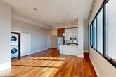 Located in New Orleans' Lower Garden District, this contemporary 1-bedroom, 1-bathroom residence offers a thoughtfully designed open-concept floor plan with rich hardwood flooring throughout. The combined living, dining, and kitchen area forms the heart of the space, bathed in abundant natural light streaming through large, black-framed floor-to-ceiling windows that frame expansive views of the New Orleans skyline and waterfront. Soaring ceilings and recessed lighting enhance the airy, modern atmosphere.

The chef's kitchen is a standout feature, showcasing a sleek island with an undermount sink and quartz countertop, warm wood cabinetry paired with white upper cabinets, stainless steel appliances including a French door refrigerator, microwave, and gas range, and stylish tiered pendant lighting overhead. An in-unit stacked washer and dryer provide added convenience.

The spacious bedroom features hardwood floors, generous wall-to-wall windows with cityscape views, and direct access to both a walk-in closet and the full bathroom. The bathroom is finished with large-format tile flooring, a floating wood vanity with a quartz countertop, backlit mirrors, and a soaking tub.
