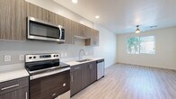 This well-designed single-floor residence offers a clean, contemporary aesthetic throughout. The kitchen serves as a functional centerpiece, outfitted with a full suite of stainless steel Whirlpool appliances, including a refrigerator, electric range, over-the-range microwave, and dishwasher. Two-toned cabinetry pairs dark lower cabinets with lighter upper cabinets featuring textured wood-grain finishes, complemented by light quartz countertops and a stainless steel sink. Recessed lighting and light wood-look flooring give the kitchen and adjoining living area a bright, open feel, with natural light streaming in through windows fitted with blinds. The bedrooms offer plush wall-to-wall carpeting, generous wall space, and ceiling fans to ensure comfort. Each room is finished with clean white walls and modern lever-style door hardware, contributing to the unit's consistent contemporary character. Two bathrooms serve the residence — one features a tub-shower combo with a curved curtain rod and light wood-look flooring, while the second presents a matching tub-shower with a stylish oval mirror and a wood-grain vanity with a white countertop. The overall ambiance is modern, clean, and move-in ready.