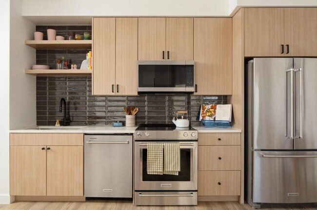 Los gabinetes de madera clara, los elegantes electrodomésticos de acero inoxidable y un protector contra salpicaduras de azulejos brillantes crean una cocina limpia y contemporánea con carácter. - Modera Rio Salado