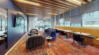 This single-floor amenity space is thoughtfully designed to offer a variety of social and recreational experiences within one cohesive layout. The space transitions seamlessly from a game area to a lounge and dining zone, all unified by consistent design elements throughout.

The game area anchors one end of the space, featuring an exposed concrete ceiling with industrial-style pendant lighting, large floor-to-ceiling windows with roller shades, and direct access to an outdoor patio. A full-size pool table serves as the focal point, while the polished concrete floors and raw ceiling give the area an urban, loft-like character.

Moving through the space, the lounge area is defined by a striking warm-toned area rug, plush velvet seating in deep navy and charcoal, and a slatted wood ceiling with integrated ambient lighting. Café-style tables and chairs line the window wall, offering comfortable seating bathed in natural light. A large wall-mounted display screen adds a functional element to the lounge.

The kitchenette is clean and modern, featuring white cabinetry, stainless steel appliances, a neutral countertop, white textured tile backsplash, open wood shelving, and an island with bar seating — ideal for casual gatherings and entertaining.