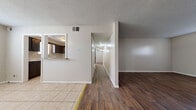 This single-story home in Emporia, Kansas offers a practical and functional layout across four bedrooms and two bathrooms. The interior is accessed through a dedicated entrance that leads into the main living areas. A central hallway connects the bedrooms and bathrooms, providing an organized flow throughout the home.

The living room features rich, dark hardwood flooring, while the adjacent dining area transitions to light tile flooring. The kitchen is equipped with white appliances, including a range and refrigerator, dark cabinetry, and a pass-through window that connects it to the dining area. Light tile flooring runs throughout the kitchen.

The four bedrooms vary in character: some feature hardwood flooring, others carpet, and several include windows fitted with blinds that allow natural light to filter in. One bedroom notably features an exposed brick accent wall, adding a distinctive architectural element.

The two bathrooms are finished with light tile flooring. One bathroom includes a tub-shower combination with tile surround and a vanity with built-in storage, while the second bathroom features a walk-in glass shower, a vanity, and a built-in shelving unit. Textured ceilings are consistent throughout the home.