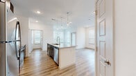 This well-appointed 2-bedroom, 2-bathroom residence in Waco, TX offers a thoughtfully designed single-floor layout with modern finishes throughout. The open-concept kitchen and living area serves as the heart of the home, anchored by a central island with granite countertops and an undermount sink, illuminated by elegant pendant lights. Rich dark cabinetry, a subway tile backsplash, and stainless steel appliances — including a refrigerator, range, and microwave — complete the kitchen. Light wood-tone flooring flows throughout the main living areas, complemented by an abundance of natural light from multiple windows fitted with white blinds. Both bedrooms feature plush carpeting, ceiling fans, and well-sized windows that bring in natural light. The primary bedroom includes its own en-suite bathroom, outfitted with a granite-topped dark vanity, a tiled tub-shower combination, built-in shelving, and wood-look flooring. The second bathroom mirrors the same refined aesthetic with a granite vanity and modern fixtures. Additional highlights include a dedicated laundry area, two closets for ample storage, and a hallway connecting the private spaces. The clean, neutral palette and contemporary design create a bright, cohesive ambiance throughout.