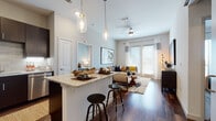 This well-designed single-floor residence offers a thoughtful open-concept layout that seamlessly connects the kitchen, dining, and living areas. Rich hardwood-style flooring runs throughout the main living spaces, anchoring the modern aesthetic. The kitchen is equipped with dark espresso cabinetry, stainless steel appliances, a tile backsplash, and a granite-topped island with bar seating, illuminated by stylish pendant lighting. The living room is bright and inviting, benefiting from generous natural light through large windows and a glass door, complemented by a ceiling fan overhead. A dedicated home office provides a quiet workspace, featuring hardwood-style flooring and ample wall space. The bedroom is a serene retreat with soft carpeting, large windows dressed in sheer curtains, and an accent wall in a muted blue-gray tone. The en-suite bathroom offers both a soaking tub and a separate walk-in shower alongside dark-finished vanity cabinetry with granite countertops. A dedicated in-unit laundry area with a full-size washer and dryer adds everyday convenience. Throughout, the space maintains a cohesive, contemporary feel with neutral tones and modern finishes.