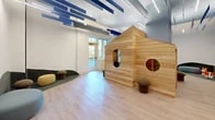 This innovative playroom, located at 2-20 Malt Drive, is a 640 square foot space designed to inspire creativity and imagination. The single-floor layout is dominated by a striking wooden playhouse, complete with circular windows and a peaked roof, serving as a centerpiece for children's activities. The room's architecture is notable for its high ceilings adorned with distinctive blue accent beams, creating a sense of openness and visual interest.

Natural light floods the space through large windows, complementing the light wood flooring that runs throughout. The room's furnishings are carefully chosen with children in mind, featuring a curved, gray seating area, colorful foam seating, and low wooden storage units filled with toys and books. These elements combine to create a safe, engaging environment for play and learning.

The playroom's design incorporates both open areas for active play and cozy nooks for quieter activities. A small kitchenette is cleverly integrated into the space, visible through an arched opening. The room's perimeter includes various activity zones, encouraging diverse forms of play and interaction.

Safety features are subtly incorporated, including rounded corners on furniture and soft seating options. The space's modern design aesthetic is balanced with warm, natural materials, creating an inviting atmosphere that appeals to both children and adults. This thoughtfully crafted playroom offers a stimulating environment for children to explore, learn, and grow.