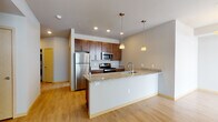 This single-floor residence in Madison, Wisconsin offers a thoughtfully designed layout with modern finishes and functional living spaces. The open-concept kitchen serves as a central highlight, featuring rich dark wood cabinetry, granite countertops, stainless steel appliances including a refrigerator, range, and microwave, and a large peninsula with an undermount sink. Pendant lighting above the peninsula adds a warm, stylish touch, while light hardwood flooring extends throughout the main living areas, creating a bright and cohesive feel.

The living spaces are well-proportioned, with natural light streaming in through large windows fitted with horizontal blinds. The bedrooms are carpeted for comfort and offer ample space, with one bedroom featuring a window with exterior views.

Two bathrooms serve the residence. The primary bathroom includes a walk-in shower stall, a dark wood vanity with a white countertop, and large-format tile flooring. The second bathroom mirrors the design aesthetic with a matching dark wood vanity, a wide mirror, and tile flooring. Both bathrooms are clean and efficiently laid out.

A hallway connects the private quarters to the main living area, providing clear separation between spaces. The overall design is modern and neutral, making this a versatile and move-in-ready residence in Madison's west side.