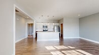 Located in New Albany, Ohio, this single-floor, 2-bedroom, 2-bathroom residence offers a thoughtfully designed layout with modern finishes throughout. The open-concept living and kitchen area serves as the heart of the home, where warm hardwood-style flooring flows beneath abundant natural light streaming through large, blinds-fitted windows. The kitchen is a standout feature, showcasing a two-tone cabinetry design with rich dark lower cabinets and crisp white uppers, complemented by white countertops, a central island, stainless steel appliances, and elegant pendant lighting overhead. The spacious primary bedroom offers plush carpeting, multiple windows, and generous closet space, while the second bedroom features hardwood-style flooring and a large picture window that fills the room with natural light. Both bathrooms are finished with white vanities and hardwood-style flooring; one includes a shower-tub combo and the other features a glass-enclosed shower. A dedicated laundry room provides added convenience, equipped with a full-size washer and dryer alongside matching two-tone cabinetry and a folding counter. Neutral gray walls and clean white trim create a cohesive, contemporary aesthetic throughout the entire home.