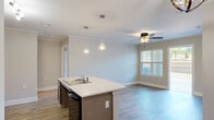 Located at 5210 Ballington Cir in Raleigh, NC, this well-appointed two-bedroom, two-bathroom home offers a thoughtfully designed single-floor layout with modern finishes throughout. The open-concept kitchen and living area serves as the heart of the home, featuring a central island with a double sink, pendant lighting, dark cabinetry with light countertops, stainless steel appliances, and crown molding. Hardwood-style flooring extends through the main living areas, adding warmth and continuity. The living room benefits from natural light through a window with exterior views and is finished with a ceiling fan. The spacious primary bedroom includes plush carpeting, a ceiling fan, and a large window that invites natural light. The second bedroom is equally well-sized with carpet and a dedicated window. Both bedrooms include closets for ample storage. One bathroom features an accessible roll-in shower with grab bars and a curtain rod, while the second offers a tub-shower combo with a stylish vanity and hardwood-style flooring. A dedicated laundry area and additional utility access are also present. Sliding glass doors in one room lead to an outdoor space, enhancing the home's connection to the exterior. The overall ambiance is clean, bright, and move-in ready.