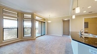 Located at 1951 Hunter Rd in San Marcos, TX, this thoughtfully designed one-bedroom, one-bathroom residence offers a comfortable and functional layout across a single floor. The open-concept living, dining, and kitchen area serves as the heart of the home, bathed in natural light streaming through large corner windows and a sliding glass door that opens to a private balcony overlooking a tree-lined neighborhood streetscape. Crown molding accents the living area's ceiling, adding a refined architectural touch, while pendant lighting and plush carpeting create a warm, inviting ambiance.

The kitchen is well-equipped with rich dark wood cabinetry, dark granite countertops, stainless steel appliances including a refrigerator and microwave, recessed lighting, and a built-in wine rack. A peninsula with a sink and additional pendant lighting connects the kitchen to the living space seamlessly.

The spacious bedroom features a ceiling fan, a bright window with outdoor views, and access to a generously sized walk-in closet complete with built-in shelving and dual hanging rods. The bathroom offers a full tiled tub-and-shower combination with a decorative mosaic accent border. Additional highlights include a dedicated laundry area with hookups and an overhead shelf, four closets for ample storage, a hallway, and a welcoming entrance foyer.