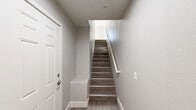 Located at 8092 W Paradise Ln in Peoria, AZ, this multi-story, 2-bedroom, 2-bathroom home is thoughtfully designed across three floors. The entry level features wood-look flooring and a staircase that leads up to the main living area. The primary floor offers an open-concept layout where the kitchen and living room flow seamlessly together. The kitchen is equipped with dark wood cabinetry, stainless steel appliances including a refrigerator, range, microwave, and dishwasher, complemented by light quartz countertops and pendant lighting. The living room features crown molding, a ceiling fan, and generous natural light. Both bathrooms include dark vanities with light countertops and wood-look flooring; one features a full tub-shower combination. The two bedrooms are carpeted and fitted with ceiling fans. The primary bedroom includes mirrored sliding closet doors, while the second bedroom offers arched windows that allow ample natural light and outdoor views. A balcony adds additional outdoor space. Throughout the home, neutral tones, clean lines, and consistent finishes create a cohesive, modern aesthetic well-suited for comfortable everyday living.