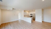 Located in Georgetown, Delaware, this single-floor, two-bedroom, two-bathroom residence offers a thoughtfully designed layout with modern finishes throughout. The open-concept kitchen and living area serves as the heart of the home, featuring white shaker-style upper cabinets, gray lower cabinetry, a classic subway tile backsplash, light quartz countertops, a peninsula with seating, and a full suite of stainless steel appliances. Light hardwood-style flooring runs throughout the main living spaces, enhancing the bright and airy ambiance created by recessed lighting. The spacious living area is highlighted by sliding glass doors that open onto a private balcony, flooding the room with natural light. Both bedrooms are carpeted for comfort, with large windows and ample closet space — five closets in total are distributed throughout the home. The primary bedroom includes a ceiling fan and generous proportions. The two bathrooms feature gray vanity cabinetry with white countertops and well-lit mirrors. A dedicated laundry area and a connecting hallway round out the functional floor plan. The clean, neutral palette and modern finishes create a cohesive and move-in-ready living environment.