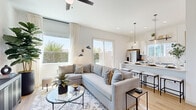 Located in Litchfield Park, AZ, this thoughtfully designed single-story home offers 2 bedrooms and 3 bathrooms within a bright, open-concept floor plan. Light wood flooring flows throughout, complementing the crisp white walls and modern aesthetic.

The living room is bathed in natural light from large windows and a sliding glass door, offering outdoor views and a welcoming, airy ambiance. A ceiling fan, stylish pendant wall sconces, and a glass-top coffee table round out the contemporary feel.

The kitchen is a standout, featuring white shaker cabinetry with matte black hardware, quartz countertops, stainless steel appliances including a French door refrigerator, and a peninsula island with seating — ideal for both cooking and casual dining. Globe pendant lights add a warm, modern touch.

The primary bedroom is a serene retreat filled with natural light, complemented by layered window treatments and warm neutral tones. A spacious walk-in closet offers built-in shelving, ample hanging rods, and high windows for natural light. The primary bathroom features a dual-sink vanity with gray cabinetry and quartz countertops.

The second bedroom is bright with multiple windows and a cheerful character. A dedicated laundry room includes a full-size washer and dryer with overhead cabinetry for additional storage.