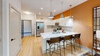 Located on Poe Drive in Raleigh, NC, this one-bedroom, one-bathroom residence offers a thoughtfully designed open-concept layout with modern finishes throughout. Light wood-style flooring flows seamlessly from the entryway through the kitchen and living areas, creating a cohesive and airy feel.

The kitchen is a standout feature, boasting white shaker cabinetry, a neutral tile backsplash, quartz countertops, and a full suite of stainless steel appliances including a refrigerator, range, microwave, and dishwasher. A peninsula with seating for multiple bar stools provides additional dining and prep space, while bold warm-toned accent walls add a vibrant, contemporary character.

The living room is filled with natural light from large windows and a glass-paneled exterior door that opens to an outdoor area, offering views of lush greenery. A ceiling fan keeps the space comfortable year-round.

The bedroom is a comfortable retreat with plush carpeting, a ceiling fan, and a generously sized window framing treetop views. A dedicated closet and convenient hallway complete the private quarters.

The bathroom features a clean, modern design with a white quartz vanity, a large mirror, a glass-enclosed shower, and light wood flooring that ties back to the main living areas. The overall design balances functionality with modern style throughout.