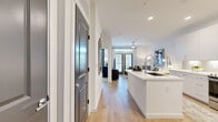 This thoughtfully designed 1-bedroom, 1-bathroom residence offers a cohesive open-concept layout that maximizes every square foot. Light wood-style flooring flows throughout the main living areas, anchoring a bright, contemporary aesthetic defined by crisp white walls and recessed lighting.

The kitchen is a standout feature, outfitted with tall white shaker cabinetry, white quartz countertops, a decorative arabesque tile backsplash, and a full suite of stainless steel appliances including a French door refrigerator, range, and over-the-range microwave. A peninsula with an undermount sink connects the kitchen seamlessly to the living area.

The living room is bathed in natural light from floor-to-ceiling glass doors that open to an outdoor patio, complemented by a ceiling fan overhead. The space offers a comfortable and functional layout suited for both relaxing and entertaining.

The bedroom features plush carpeting, a large window that brings in abundant natural light, and a ceiling fan. It connects directly to a well-proportioned walk-in closet with dual hanging rods and built-in shelving. The full bathroom includes a white vanity with quartz countertop and a glass-enclosed walk-in shower with marble-style tile surround.