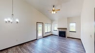 This single-floor home offers a thoughtfully designed layout with a cohesive blend of modern finishes and functional living spaces. The living room is a standout area, boasting soaring vaulted ceilings, wood-look luxury vinyl plank flooring, and a tile-surround fireplace with a wood mantel. Multiple windows and a glass-paned exterior door flood the space with natural light and offer views of the surrounding landscape, while a ceiling fan adds comfort overhead.

The kitchen is well-equipped with rich dark cabinetry, granite countertops, stainless steel appliances including a refrigerator with ice maker, electric range, and microwave. A large granite-topped island with pendant lighting serves as a central focal point, and an additional galley-style prep area provides ample counter and storage space.

The bathrooms feature dark vanity cabinetry, granite countertops, wood-look flooring, and well-lit mirrors. The primary bath includes a glass-door walk-in shower, while a secondary full bath offers a tub and a natural light window. Bedrooms are carpeted, ceiling fan-equipped, and receive good natural light. A dedicated laundry room houses a full-size washer and dryer. The spacious walk-in closet includes multi-level wire shelving for generous storage.