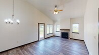 This single-floor home offers a thoughtfully designed layout with a cohesive blend of modern finishes and functional living spaces. The living room is a standout area, boasting soaring vaulted ceilings, wood-look luxury vinyl plank flooring, and a tile-surround fireplace with a wood mantel. Multiple windows and a glass-paned exterior door flood the space with natural light and offer views of the surrounding landscape, while a ceiling fan adds comfort overhead.

The kitchen is well-equipped with rich dark cabinetry, granite countertops, stainless steel appliances including a refrigerator with ice maker, electric range, and microwave. A large granite-topped island with pendant lighting serves as a central focal point, and an additional galley-style prep area provides ample counter and storage space.

The bathrooms feature dark vanity cabinetry, granite countertops, wood-look flooring, and well-lit mirrors. The primary bath includes a glass-door walk-in shower, while a secondary full bath offers a tub and a natural light window. Bedrooms are carpeted, ceiling fan-equipped, and receive good natural light. A dedicated laundry room houses a full-size washer and dryer. The spacious walk-in closet includes multi-level wire shelving for generous storage.