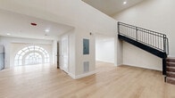Located at 501 Washington St in Reading, PA, this two-story residence offers a well-designed layout spread across two generously sized floors. The main level features an open kitchen and living area anchored by a stunning arched window that floods the space with natural light. The kitchen is outfitted with shaker-style gray cabinetry, matte black hardware, and a full suite of stainless steel appliances including a range, microwave, dishwasher, and refrigerator, all set above light-toned hardwood-style flooring that flows throughout the main living areas. A sleek staircase with black metal railings connects the two floors. Upstairs, two carpeted bedrooms offer comfortable retreats, each with windows framing views of the surrounding urban streetscape. The primary bedroom provides a generous footprint with an adjoining hallway leading to additional storage or access. Both bathrooms are finished with clean, modern fixtures, including shaker-style vanities, white countertops, round mirrors with black frames, and light wood flooring. The overall aesthetic is bright, contemporary, and move-in ready, with crisp white walls and recessed lighting throughout contributing to a clean, cohesive ambiance ideal for urban living.