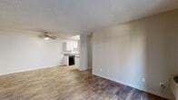 This single-floor unit is located in Hayward, CA (94541) and offers a straightforward, functional layout designed for comfortable everyday living. The open living area is finished with wood-look plank flooring and features a ceiling fan overhead, with a textured ceiling adding a classic touch throughout the main spaces. A passthrough connects the living area to the kitchen, which is equipped with white upper and lower cabinetry, gray countertops, a stainless steel sink, a black dishwasher, a gas cooktop range, and a refrigerator. Overhead fluorescent lighting keeps the kitchen well-lit. The bedroom is carpeted and benefits from multiple windows that invite natural light and offer views of the surrounding community. A baseboard heater provides warmth, and the room includes access to a spacious walk-in closet outfitted with dual shelving rods on both sides, offering generous storage capacity. The bathroom features a clean, white tub and shower combination with chrome fixtures, complemented by neutral-toned walls and tile flooring. A sliding glass door in the living area provides access to the exterior, enhancing the connection between indoor and outdoor space.