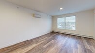 Located at 11 Park St in Essex Junction, Vermont, this efficiently designed single-floor unit offers a thoughtful layout that maximizes every inch of available space. The open-concept kitchen and living area serves as the heart of the unit, featuring rich hardwood-style flooring throughout, recessed lighting, and multiple windows that invite abundant natural light and offer views of the surrounding neighborhood. The kitchen is outfitted with crisp white cabinetry, dark countertops, a classic subway tile backsplash, and a full suite of stainless steel appliances including a range, microwave, dishwasher, and refrigerator. A stylish sliding barn door adds a modern farmhouse touch, neatly separating spaces while enhancing the unit's character. The living area is bright and open, equipped with a wall-mounted mini-split system for year-round climate control and baseboard heating as a supplemental option. The bathroom is elegantly finished with large-format tile flooring, a dark wood vanity with a white countertop, and a glass-enclosed walk-in shower with floor-to-ceiling tile surround. Two closets provide practical storage, while a dedicated laundry area adds everyday convenience. This unit combines clean, contemporary finishes with functional design for comfortable living.