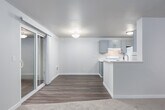 This single-floor unit offers a well-organized layout with distinct living, sleeping, and functional zones. The living room is a standout space, featuring a tiled fireplace flanked by two windows that bring in natural light and offer views of surrounding greenery. Neutral carpet and light-toned walls create a calm, open atmosphere throughout the room.

The kitchen is designed for efficient use of space, featuring gray shaker-style cabinetry, white quartz-style countertops, and white appliances including a range and refrigerator. A peninsula counter separates the kitchen from the adjoining living area, providing additional workspace and a visual connection between the two zones. Wood-look flooring ties the kitchen and dining areas together cohesively.

Multiple bedrooms are carpeted and include large windows with outdoor views and baseboard heating. Each room offers closet access, with at least one featuring a sliding panel closet door.

The bathroom is finished with gray cabinetry, a speckled white countertop, undermount sink with brushed nickel fixtures, and a full tub-shower combination. Clean white walls and wood-look flooring complete the functional, updated aesthetic throughout the space.