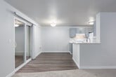 This single-floor unit offers a well-organized layout with distinct living, sleeping, and functional zones. The living room is a standout space, featuring a tiled fireplace flanked by two windows that bring in natural light and offer views of surrounding greenery. Neutral carpet and light-toned walls create a calm, open atmosphere throughout the room.

The kitchen is designed for efficient use of space, featuring gray shaker-style cabinetry, white quartz-style countertops, and white appliances including a range and refrigerator. A peninsula counter separates the kitchen from the adjoining living area, providing additional workspace and a visual connection between the two zones. Wood-look flooring ties the kitchen and dining areas together cohesively.

Multiple bedrooms are carpeted and include large windows with outdoor views and baseboard heating. Each room offers closet access, with at least one featuring a sliding panel closet door.

The bathroom is finished with gray cabinetry, a speckled white countertop, undermount sink with brushed nickel fixtures, and a full tub-shower combination. Clean white walls and wood-look flooring complete the functional, updated aesthetic throughout the space.