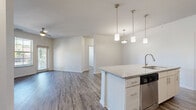 Located at 860 Candlelite Ln. in Columbus, Ohio, this single-floor, 3-bedroom, 2-bathroom home offers a well-designed open-concept layout. The combined kitchen and living area serves as the heart of the home, featuring durable wood-style flooring, a ceiling fan, and sliding door access to a private patio that brings in generous natural light. The kitchen is appointed with white cabinetry, a subway tile backsplash, granite countertops, stainless steel appliances, and a central island with pendant lighting and an integrated sink — ideal for both cooking and casual dining. The spacious living area flows seamlessly from the kitchen, creating a cohesive and functional common space. Each of the three bedrooms is carpeted and includes window blinds that provide natural light and privacy; the secondary bedrooms feature closets with paneled double doors. The two bathrooms are finished with granite-topped vanities and wood-style flooring; the full bath includes a tiled tub-shower surround. A dedicated laundry room houses a full-size washer and dryer. With four closets and a utility room, storage is plentiful throughout. The home's neutral palette and modern finishes create a clean, move-in-ready atmosphere.