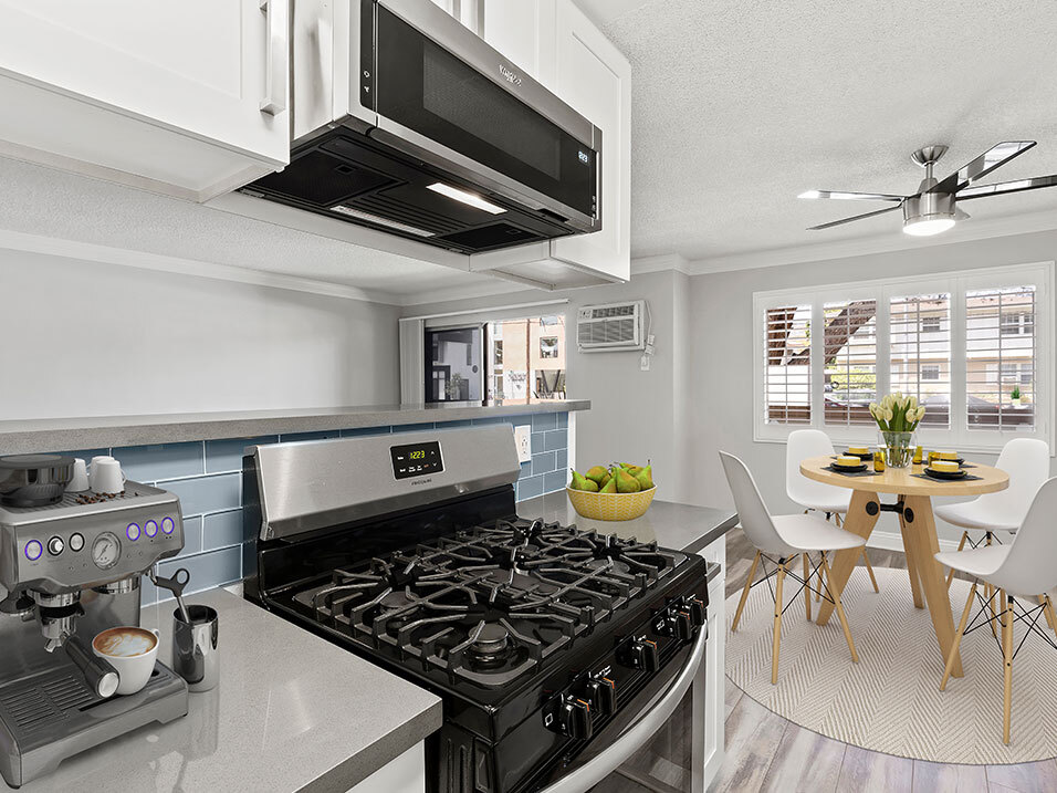 Blue tiled kitchen with stainless steel oven and microwave and view of hardwood floor dining room. - National Apartments