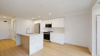 Located at 1470 Queen Street in Halifax, Nova Scotia, this thoughtfully designed one-bedroom, one-bathroom unit offers a clean, modern aesthetic throughout. Light hardwood flooring flows seamlessly across the entire space, enhancing the bright, open feel.

The kitchen is a standout feature, showcasing floor-to-ceiling white cabinetry, a marble-look tile backsplash, and a striking central island with a waterfall marble countertop, an undermount sink, and warm wood-panel detailing. Stainless steel appliances — including a French door refrigerator, electric range, and built-in microwave — complete the contemporary culinary space. Recessed lighting illuminates the open-concept living and kitchen area.

A hallway connects the main living space to the bedroom, bathroom, and closet. The bedroom is a compact, well-proportioned room featuring a window for natural light and access to a dedicated closet with built-in shelving for organized storage.

The bathroom is finished in a clean, neutral palette with large-format tile flooring, a frameless sliding glass shower enclosure, and a vanity with a stone countertop.

Additional highlights include a private balcony and in-unit laundry. This unit combines efficient use of space with refined, modern finishes ideal for contemporary urban living.