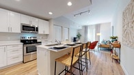 This single-floor residence offers a thoughtfully designed open-concept layout that seamlessly connects the kitchen, dining, and living areas. The kitchen is a standout feature, equipped with stainless steel appliances, including a French door refrigerator, range, microwave, and dishwasher. Crisp white shaker cabinetry extends to the ceiling, providing generous storage, while the center island with a quartz countertop accommodates bar seating, making it ideal for casual dining and entertaining. Wood-look flooring runs throughout the space, adding warmth and visual continuity.

The living area is bright and welcoming, benefiting from a large sliding glass door that floods the room with natural light. The two bedrooms are comfortably sized, each featuring the same warm wood-look flooring and easy access to their respective bathrooms. The primary bedroom includes ample space for a seating area, while the secondary bedroom offers a cozy, well-appointed retreat.

Both bathrooms feature walk-in showers with tiled surrounds and wood-look flooring, maintaining a consistent, clean aesthetic. Recessed lighting and track lighting are found throughout, ensuring well-lit spaces across the entire residence.