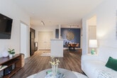 This single-floor residence in Lawrenceville, GA offers a thoughtfully designed open-concept layout that seamlessly connects the kitchen, dining, and living areas. The kitchen features dark cabinetry with granite-style countertops, a tiled backsplash, black appliances, and a breakfast bar with bar seating, providing both functionality and a contemporary aesthetic. Wood-look flooring flows throughout the main living areas, adding warmth and cohesion.

The dining area is defined by a bold teal accent wall, a round mirror, and floating wooden shelves, creating an intimate yet stylish setting. Adjacent to it, the living room is bright and welcoming, benefiting from natural light through windows dressed with patterned drapes. Track lighting in the kitchen and open sightlines throughout the main area enhance the sense of space.

The bedroom features plush carpet, a ceiling fan, and multiple windows that allow generous natural light, lending a calm and restful atmosphere. The en-suite hallway leads directly to a well-appointed bathroom with dark vanity cabinetry, granite-style countertops, and a tub-shower combination. A second bathroom mirrors this design with wood-look flooring and a dark vanity. An in-unit laundry area adds further convenience to this well-appointed home.