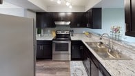 This two-floor home offers a clean, modern aesthetic with a neutral gray color palette carried consistently throughout. The welcoming entryway opens to a bright living area featuring durable hardwood-style plank flooring and large windows that draw in abundant natural light and offer views of the surrounding neighborhood.

The kitchen is a standout feature, showcasing rich dark cabinetry paired with light granite countertops, stainless steel appliances including a range and refrigerator, a stainless steel sink, and track lighting overhead — a functional and stylish space for cooking and entertaining.

Adjacent living and dining areas continue the hardwood-style flooring, while the bedrooms upstairs are finished with plush gray carpeting and large windows that provide ample natural light and neighborhood views. Textured ceilings add a classic touch throughout.

The home includes multiple bathrooms, each featuring dark vanity cabinetry, white countertops, and chrome fixtures. One bathroom offers a single vanity and toilet, while others include a full tub-shower combination. All bathrooms are finished with hardwood-style flooring for easy maintenance.

Overall, the space presents a cohesive, move-in-ready interior with practical finishes, generous natural light, and a consistent modern design sensibility across both floors.