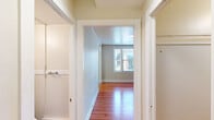 Located at 1330 Boren Ave in Seattle, WA, this one-bedroom, one-bathroom unit offers a thoughtfully arranged single-floor layout. The spacious bedroom is the highlight of the home, featuring warm hardwood flooring, a ceiling fan with light fixture, and two windows that invite natural light and views of the surrounding neighborhood. Built-in shelving along one wall adds both character and practical storage. The bedroom connects to a generously sized walk-in closet with hardwood floors and full-length clothing rods, providing ample storage. The kitchen is efficiently laid out with light tile-style flooring, a stainless electric range, and a full-size refrigerator, complemented by a window that brings in natural light. The bathroom is clean and functional, featuring a pedestal sink, a mirrored medicine cabinet, a window for ventilation, and tile-style flooring. A hallway connects the rooms, creating a cohesive and easy-to-navigate floor plan. Neutral tones throughout the unit lend a bright and airy feel, while the hardwood flooring in the main living areas adds warmth and a classic aesthetic to the overall space.