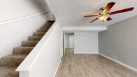 Located at 2731 N Valencia Ave in Fayetteville, Arkansas, this two-story residence offers a practical and well-appointed layout across two levels. The main floor features a bright, open living area finished with light-toned luxury vinyl plank flooring, neutral gray walls, and a ceiling fan overhead. A carpeted staircase leads to the upper level, and natural light filters in through blinded windows, creating a welcoming atmosphere throughout.

The kitchen is thoughtfully designed with white shaker-style cabinetry, granite countertops, a stainless steel double-basin sink with a modern pull-down faucet, and stainless steel appliances including an electric range and refrigerator. The LVP flooring continues seamlessly into this space.

The bedrooms are carpeted for comfort and feature ceiling fans, natural light from sizable windows, and individual closets for ample storage. A bathroom includes a granite-topped vanity with white cabinetry and brushed nickel hardware, consistent with the finishes found throughout the home.

A dedicated in-unit laundry area with side-by-side washer and dryer hookups provides added convenience, complete with overhead shelving and LVP flooring. Textured ceilings are present throughout, and the overall design maintains a clean, neutral palette that offers a versatile backdrop for any style.
