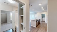 Located at 6854 Governors West NW in Huntsville, Alabama, this well-appointed two-bedroom, two-bathroom residence offers a thoughtfully designed single-level layout. The kitchen serves as the heart of the home, showcasing rich dark-wood cabinetry, granite countertops, a large center island with a built-in sink, subway tile backsplash, and stainless steel appliances including a refrigerator, range, and microwave. Wood-look flooring flows throughout the main living and kitchen areas, adding warmth and continuity to the space. The primary bedroom features a tray ceiling with a ceiling fan, natural light from large windows with outdoor views, and direct access to a well-appointed en-suite bathroom complete with granite vanity, dark cabinetry, and a walk-in closet with built-in shelving. The second bedroom also benefits from a ceiling fan, plush carpeting, a walk-in closet, and bright window views. Both bathrooms are finished with wood-look flooring and clean, neutral tones. A dedicated laundry room provides added convenience with in-unit washer and dryer hookups. Neutral wall colors and consistent finishes throughout give the home a cohesive and move-in-ready appeal.