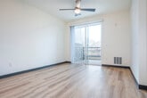 Located on E Main St in Sun Prairie, WI, this thoughtfully designed one-bedroom unit offers a modern living experience with a well-appointed, open-concept layout. The kitchen serves as the centerpiece of the main living area, featuring stainless steel appliances including a refrigerator, range, microwave, and dishwasher, complemented by crisp white subway tile backsplash and light wood cabinetry. A spacious central island with a white quartz-style countertop provides additional prep space and casual seating, while a pair of globe pendant lights with brass accents add a stylish, contemporary touch. Light hardwood flooring flows seamlessly throughout the entire unit, enhancing the bright and airy atmosphere created by the neutral white walls. The open living area extends toward sliding glass doors that lead to a private balcony, offering outdoor views of the surrounding landscape. A ceiling fan in the living space ensures year-round comfort. The bedroom is a comfortable, well-lit retreat with a large window that brings in natural light and provides outdoor views. Two closets offer ample storage throughout the unit. The overall design aesthetic is clean and modern, with consistent finishes that create a cohesive, move-in-ready living space.