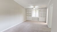 Located at 1940 Poplar Ridge Pl in Fort Wayne, Indiana, this single-floor, three-bedroom, one-bathroom home offers a practical and comfortable layout. The spacious primary bedroom is a standout feature, boasting floor-to-ceiling built-in bookshelves flanking a window, a ceiling fan with light fixture, and soft neutral carpet — creating a bright, organized retreat. A second bedroom features a built-in low-profile storage unit beneath its window, adding functional charm, while a third bedroom offers a clean, carpeted space with crown molding and ample wall space. The kitchen is equipped with rich warm-toned wood cabinetry, granite-look countertops, a dishwasher, a range, and a refrigerator, all set on light tile flooring with a window for natural light. It opens conveniently toward the primary bedroom area. The full bathroom includes a tub-shower combo, a vanity with wood cabinetry, and tile flooring. A dedicated laundry room houses a full-size washer and dryer alongside upper wood cabinets and a water heater. Crown molding and neutral tones are consistent throughout, lending a cohesive and tidy aesthetic to the entire home.