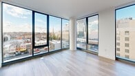 Located in the heart of downtown Wilmington at 801 N Orange St, this contemporary 3-bedroom, 1-bathroom residence offers a sleek, modern design defined by expansive floor-to-ceiling windows that flood every room with natural light and frame striking panoramic views of the city skyline. Light-toned hardwood flooring runs throughout, complementing the clean white walls and minimalist aesthetic.

The open-concept kitchen and living area serves as the centerpiece of the home. The kitchen features gray cabinetry with black hardware, white quartz countertops, stainless steel appliances, and a large center island with a built-in sink — all illuminated by modern pendant lighting and city views through a full-height window.

The three bedrooms are well-proportioned, each benefiting from large windows that capture views of Wilmington's urban landscape, including notable landmarks and the surrounding neighborhood. The spacious primary bedroom offers a generous footprint with ample natural light.

The bathroom is finished with large-format tile flooring, a warm wood vanity with white countertop, and a full tub-shower combination clad in dramatic marble-style tile. The overall ambiance of this residence is bright, airy, and distinctly urban — ideal for those seeking sophisticated city living in downtown Wilmington.
