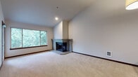 This single-floor space is thoughtfully laid out, offering a cohesive blend of comfort and functionality across its well-defined rooms. The entryway features rich hardwood flooring that extends through the hallways, creating a warm and inviting introduction to the home.

The spacious living room is a standout area, boasting soaring vaulted ceilings that lend an airy, open atmosphere. A corner brick fireplace serves as a natural focal point, while large sliding and picture windows frame lush, verdant outdoor views and allow abundant natural light to fill the room. Plush wall-to-wall carpeting adds warmth underfoot.

The kitchen is equipped with dark espresso cabinetry, granite countertops, stainless steel appliances, and a breakfast bar, complemented by a dedicated pantry for ample storage. Hardwood flooring carries throughout this area.

The bedrooms are generously proportioned and carpeted, each featuring windows that offer pleasant outdoor views, with baseboard heating ensuring year-round comfort. One bedroom provides access to a balcony.

The bathrooms are well-appointed, with the primary bath offering dual vanities with dark cabinetry, a separate walk-in shower, a soaking tub, and hardwood flooring. An in-unit laundry area adds everyday convenience to this practical and comfortable space.