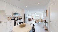 This well-appointed 2-bedroom, 2-bathroom residence at 1001 Innovation Dr offers a clean, modern aesthetic throughout its thoughtfully designed single-floor layout. The living room is bright and welcoming, featuring a ceiling fan, light-toned flooring, and a large window fitted with blinds that frame outdoor views and fill the space with natural light. The kitchen is outfitted with crisp white cabinetry extending to the ceiling, stainless steel appliances including a refrigerator, electric range, over-the-range microwave, and dishwasher, complemented by light countertops and light wood-style flooring. The primary bedroom is a comfortable retreat, featuring a ceiling fan, a large window with outdoor views, and soft carpeting. The second bedroom offers a cozy, well-lit atmosphere with similar light finishes. Both bathrooms are finished in a consistent, clean palette with white vanities, tub-shower combinations with tiled surrounds, light wood-style flooring, and recessed lighting. Each bedroom is paired with a dedicated closet featuring wire shelving systems that maximize storage. The overall ambiance throughout the residence is light, airy, and modern, with a cohesive neutral color scheme that creates a calm and functional living environment.