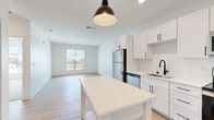 This thoughtfully designed 2-bedroom, 2-bathroom unit at 2200 Northwestern Ave in Racine, Wisconsin offers a clean, modern aesthetic across a single floor. The open-concept living and kitchen area serves as the heart of the home, featuring light wood-style flooring, white shaker cabinets with matte black hardware, stainless steel appliances including a refrigerator, dishwasher, range, and microwave, and a matte black sink faucet. A central kitchen island with a white countertop and stylish pendant lighting adds both functionality and visual appeal. Recessed lighting and a window overlooking the exterior fill the living area with natural light, creating a bright and airy atmosphere.

Both bedrooms are carpeted and generously proportioned, with the primary bedroom offering a spacious layout. The primary bath features warm wood-tone flooring, a white vanity with ample drawer storage, matte black fixtures, and direct access to a walk-in closet outfitted with wire shelving. The second bathroom includes a soaking tub and matching finishes, maintaining the unit's cohesive contemporary style. An additional dedicated closet provides further storage. Clean white walls and consistent modern hardware tie the entire space together with a fresh, move-in-ready appeal.