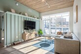 Located at 301 N Broom St in Madison, WI, this single-floor 5-bedroom, 2-bathroom unit showcases a modern design anchored by a distinctive wood-plank ceiling that runs throughout the main living areas, adding warmth and architectural character. The open-concept kitchen and living room form the heart of the space, where light-toned cabinetry, stainless steel appliances, a subway tile backsplash, and a peninsula with bar seating create a functional yet stylish setting. Pendant lighting and track fixtures complement the natural light that pours in through large floor-to-ceiling windows. The living room opens directly onto a private balcony, offering views of the surrounding Madison cityscape. In-unit stacked washer and dryer add everyday convenience. Each of the five bedrooms features sliding barn-style doors, built-in shelving, and hardwood-style flooring, with several rooms benefiting from elevated ceilings that enhance the sense of space. The primary bedroom is comfortably sized with clean, minimalist finishes. Both bathrooms are outfitted with glass-enclosed walk-in showers, rain showerheads, handheld fixtures, built-in shelving, and modern vanities with ample counter space, delivering a refined, hotel-like experience throughout.